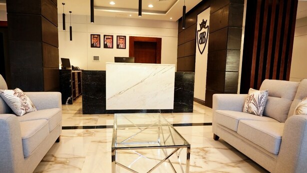 A hotel lobby with a reception desk, two sofas, a glass coffee table, and a marble floor. - BAITY Boutique Hotel (Aqaba)
