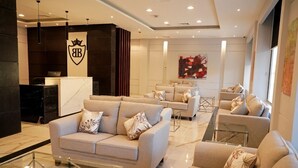 Un moderno vestíbulo de hotel con mostrador de recepción, sofás y una mesa de centro de vidrio.