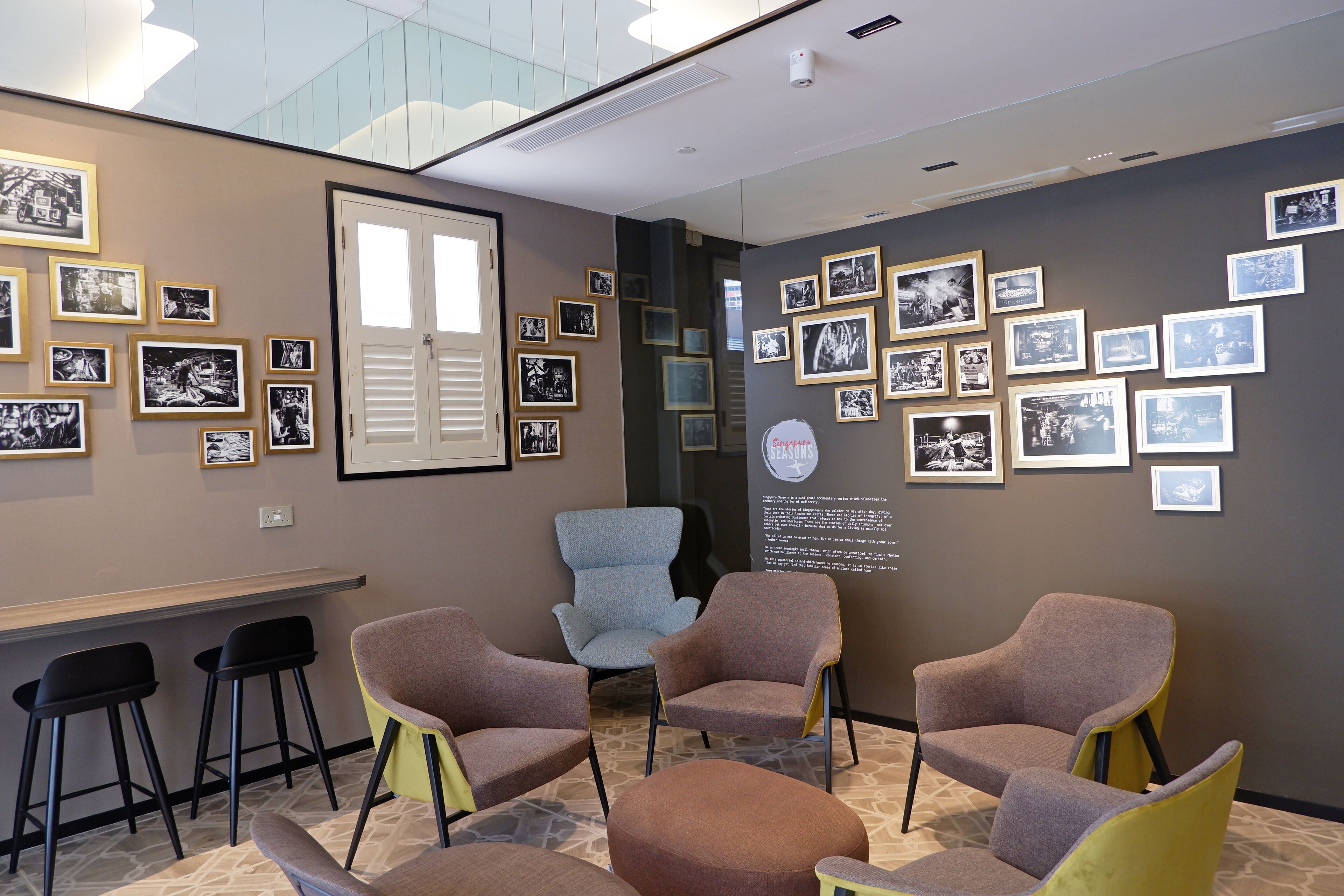 A modern interior with a seating area, framed photographs on the walls, and a glass ceiling.