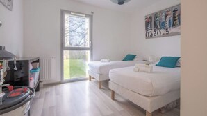 A modern bedroom with two beds, a kitchenette, and a large window. - Spacious accommodation, private garden 1200m from Léa baule beach (Guerande (Beslon))