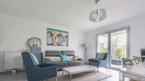 A modern living room with a grey sofa, two blue armchairs, a white coffee table, and a painting above the sofa. - Spacious accommodation, private garden 1200m from Léa baule beach (Guerande (Beslon))