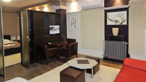 A modern living room with a sofa, a coffee table, a TV, and a dining area with chairs and a table. - Vila Ambasador Bratin Dol (Bratin Dol)