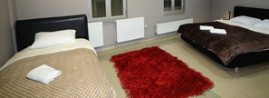 Ett hotellrum med två sängar, en röd matta och vita element.