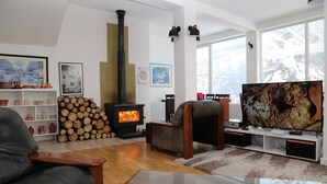 A modern living room with a fireplace, a television, and a sofa. - Vila Ambasador Bratin Dol (Bratin Dol)