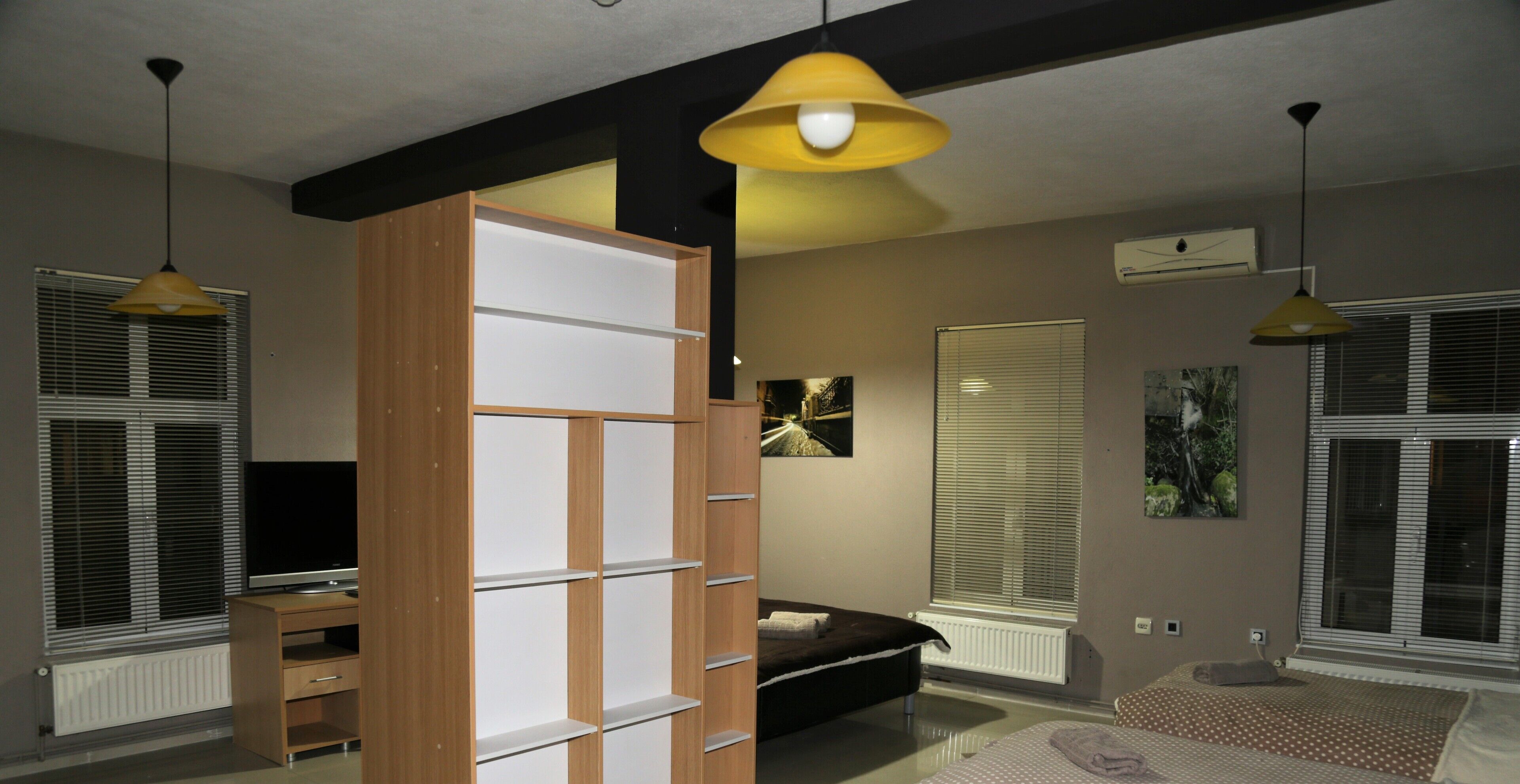 A modern bedroom with a bed, a TV, and a wooden wardrobe.