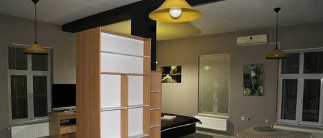 A modern bedroom with a bed, a TV, and a wooden wardrobe.