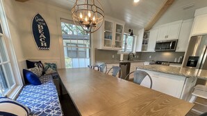 A modern kitchen with white cabinets, a wooden dining table, and a built-in oven.