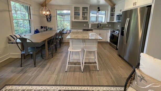 A modern kitchen with a large island, white cabinetry, and stainless steel appliances.