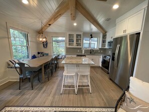 A modern kitchen with a large island, white cabinetry, and stainless steel appliances.