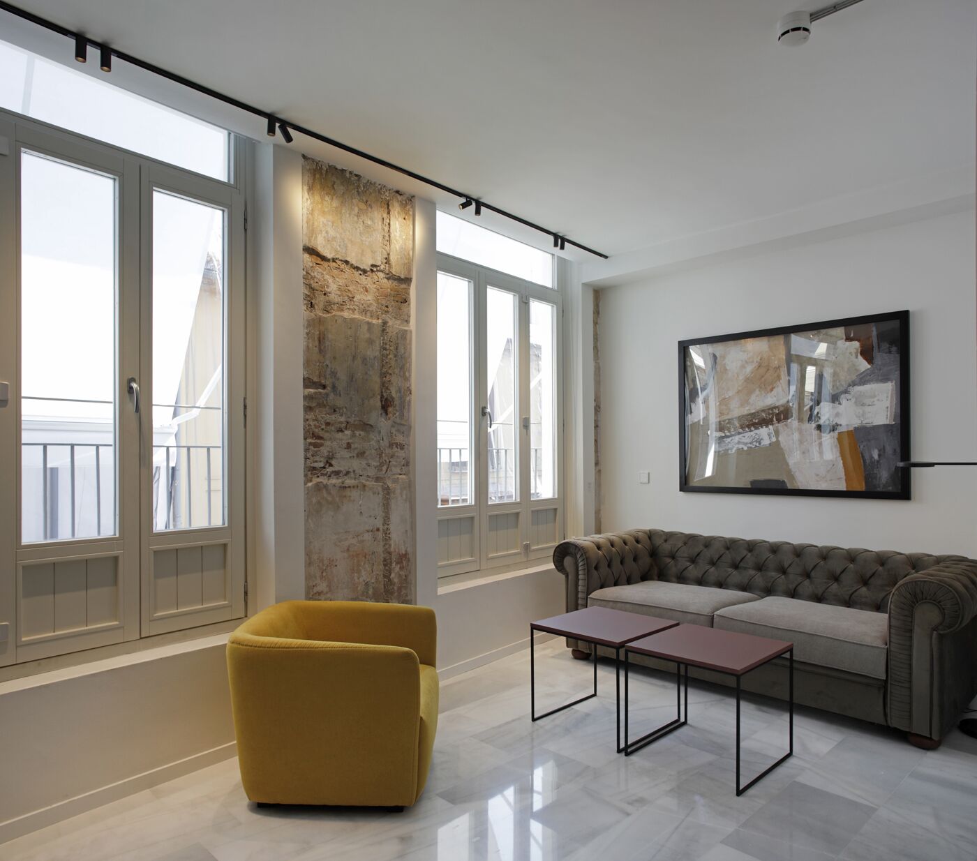 A modern living room with a large window, a yellow armchair, a gray sofa, and a minimalist coffee table.