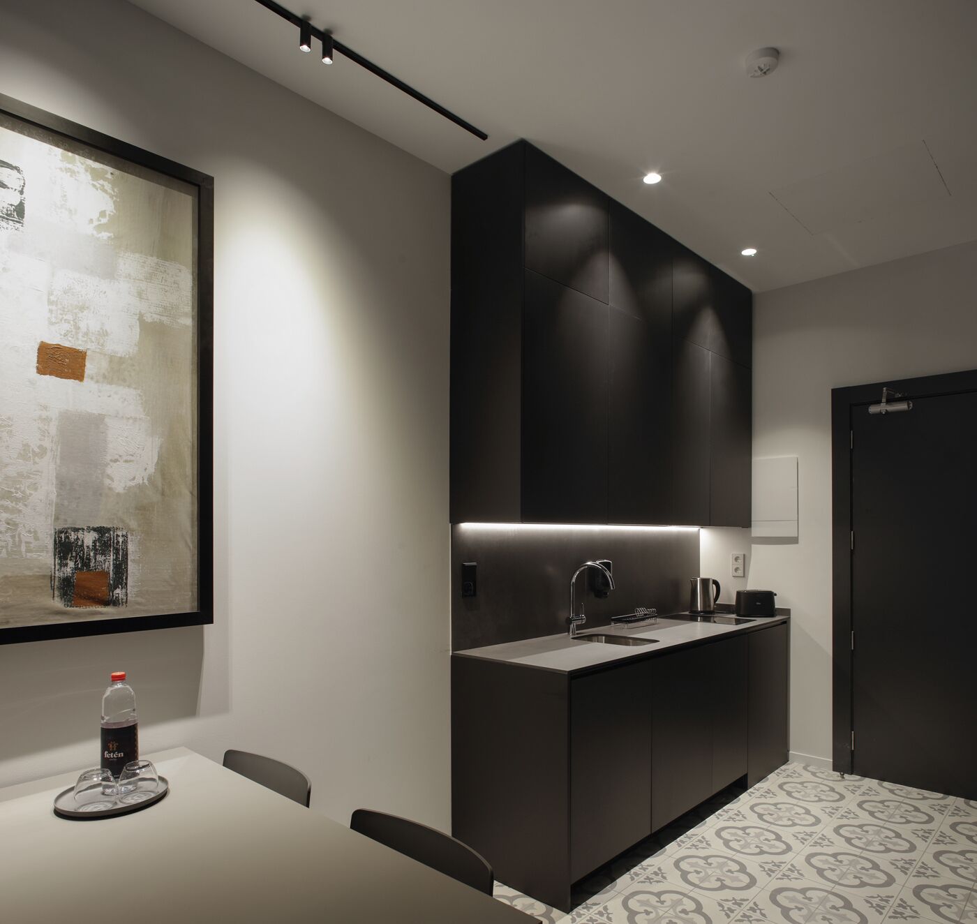 Una cocina moderna con muebles oscuros, un lavamanos de acero inoxidable y una encimera.