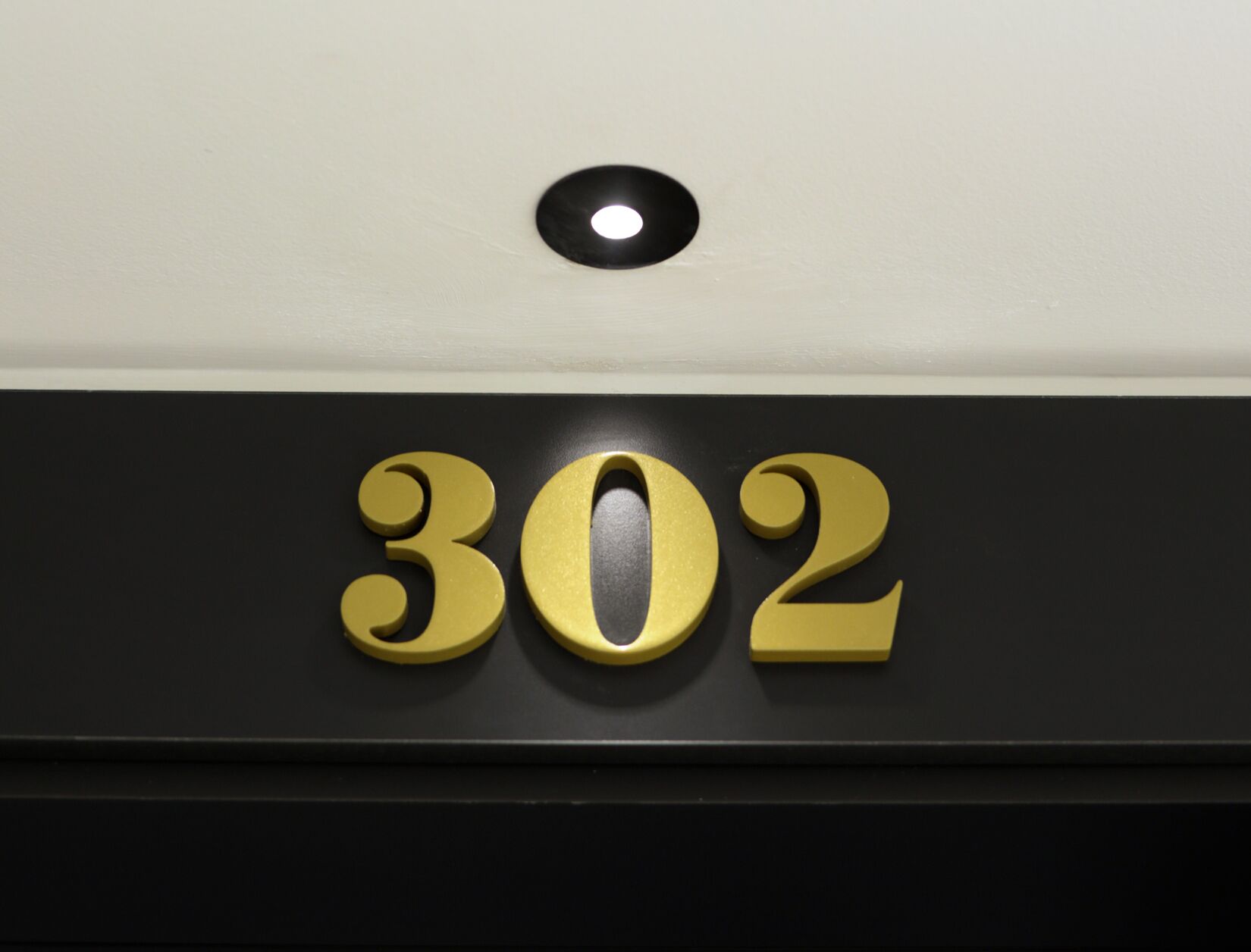 Un letrero negro y dorado con el número 302.