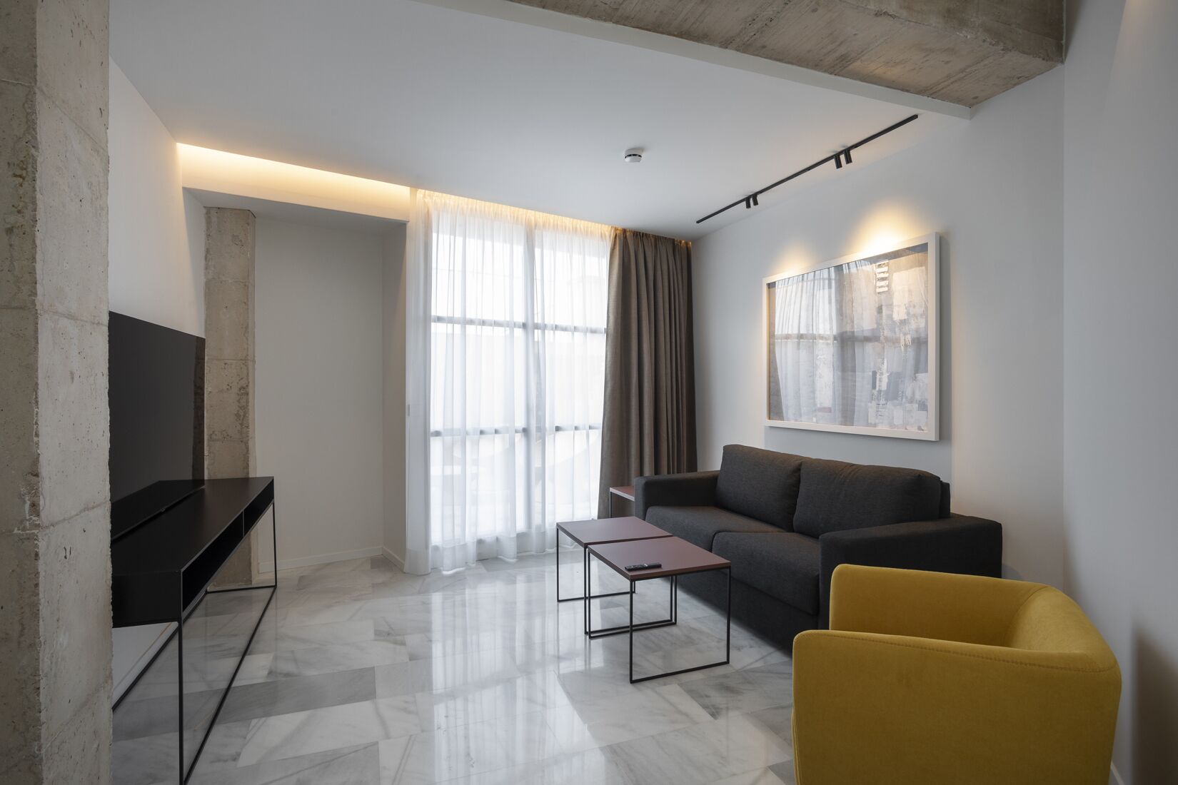 A modern living room with a sofa, a yellow armchair, a coffee table, and a TV.