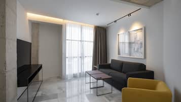 A modern living room with a sofa, a yellow armchair, a coffee table, and a TV.