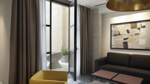 A modern living room with a sofa, a yellow chair, a glass partition, and a large abstract painting on the wall. - Mon Suites Fetén (Valencia)