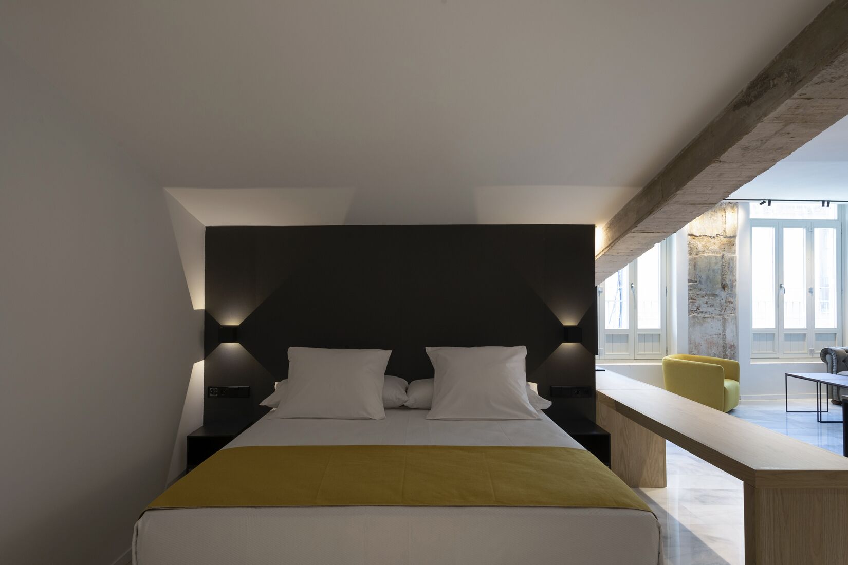 Un dormitorio moderno con una cama, mesitas de noche y un banco.