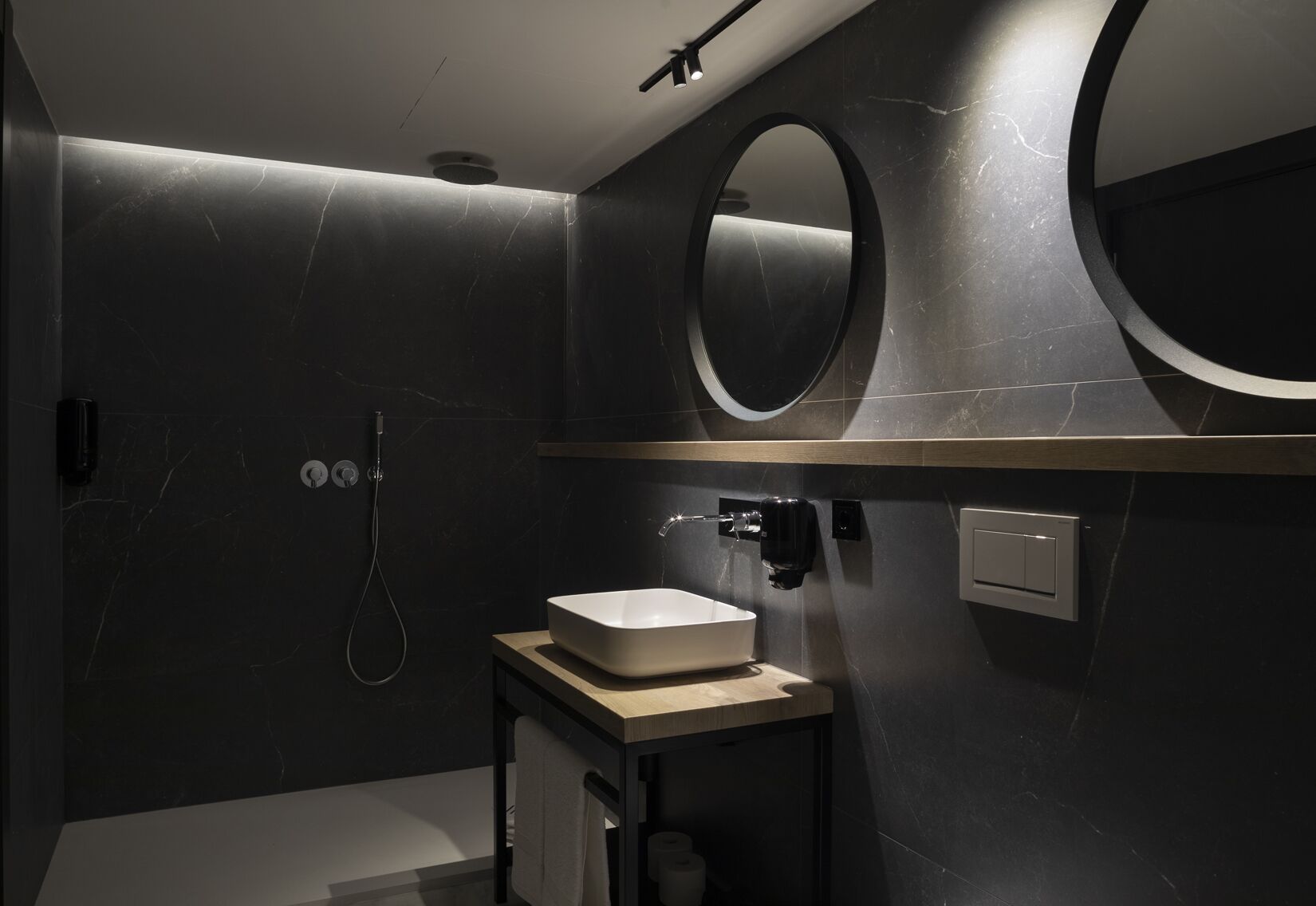 Une salle de bain moderne avec un grand miroir, un lavabo et une douche.