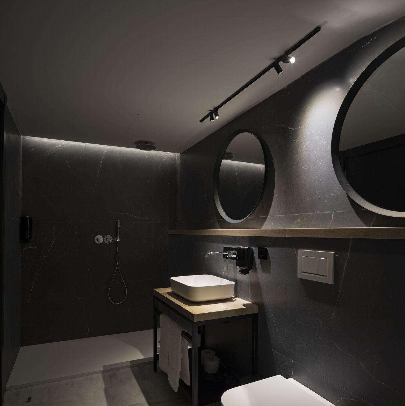 A modern bathroom with a large mirror, a sink, and a shower.