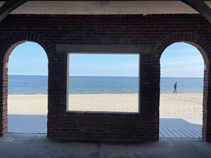 A beach view through a brick structure with arched openings.