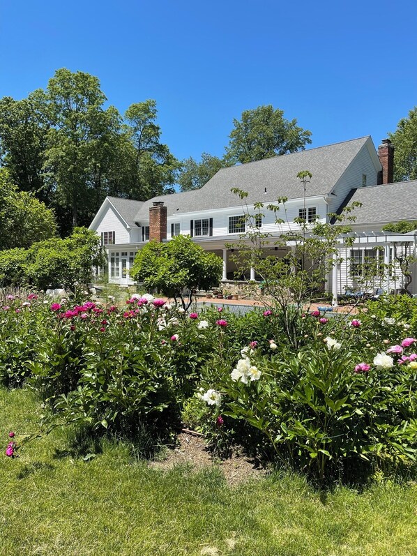 A large house with a covered porch and a garden with blooming flowers.