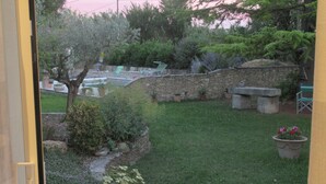 Un muro de piedra con un banco y un pequeño jardín, con un árbol y plantas en macetas.