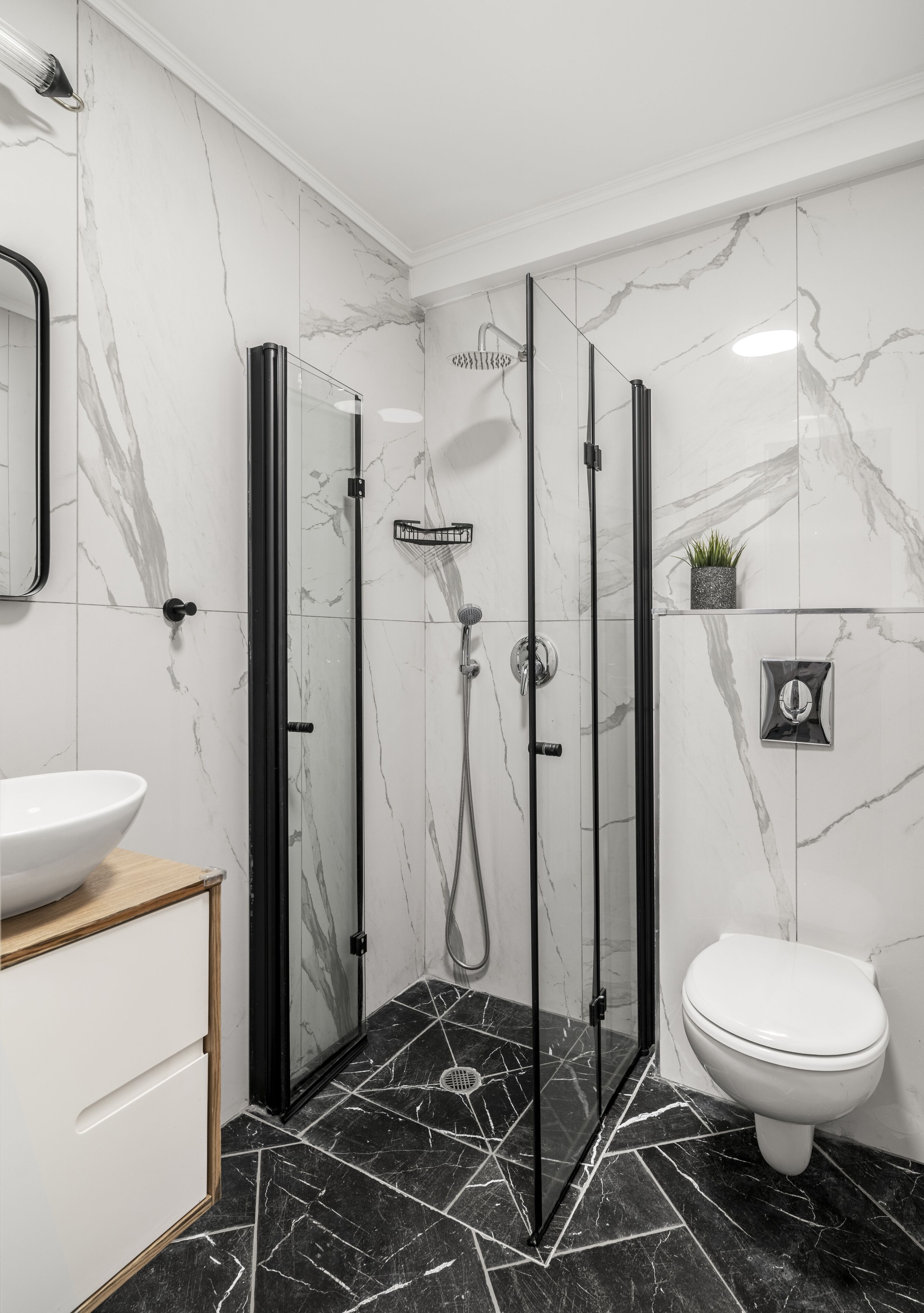 Un bagno moderno con cabina doccia in vetro, un water bianco e un pavimento in marmo.