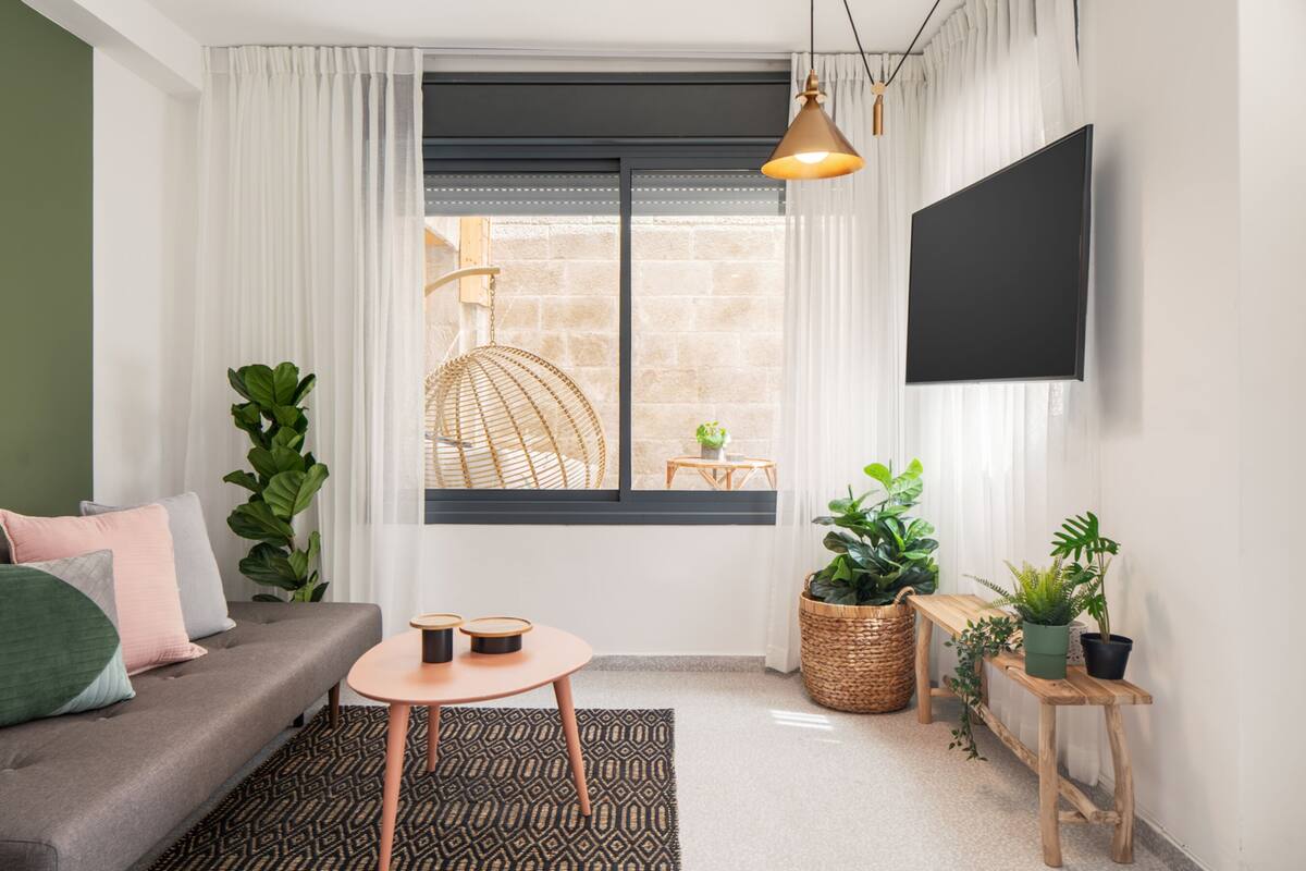 A modern living room with a sofa, a round table, and a TV mounted on the wall.