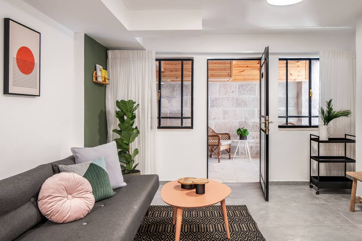 A modern living room with a grey sofa, a round wooden coffee table, and a large green plant.