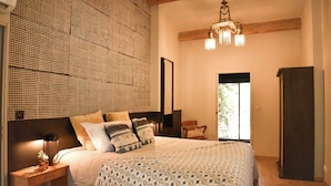 Une chambre à coucher avec une tête de lit à motifs, un lit avec de nombreux oreillers, une table de chevet avec une lampe et un lustre.