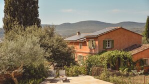 Une villa avec piscine, entourée de verdure et avec des montagnes en toile de fond.