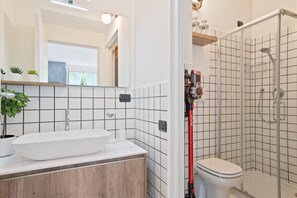 Moderni kylpyhuone, jossa on valkoinen pesuallas, peili ja laatoitetut seinät.