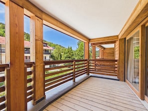 A wooden balcony with a view of buildings and trees.