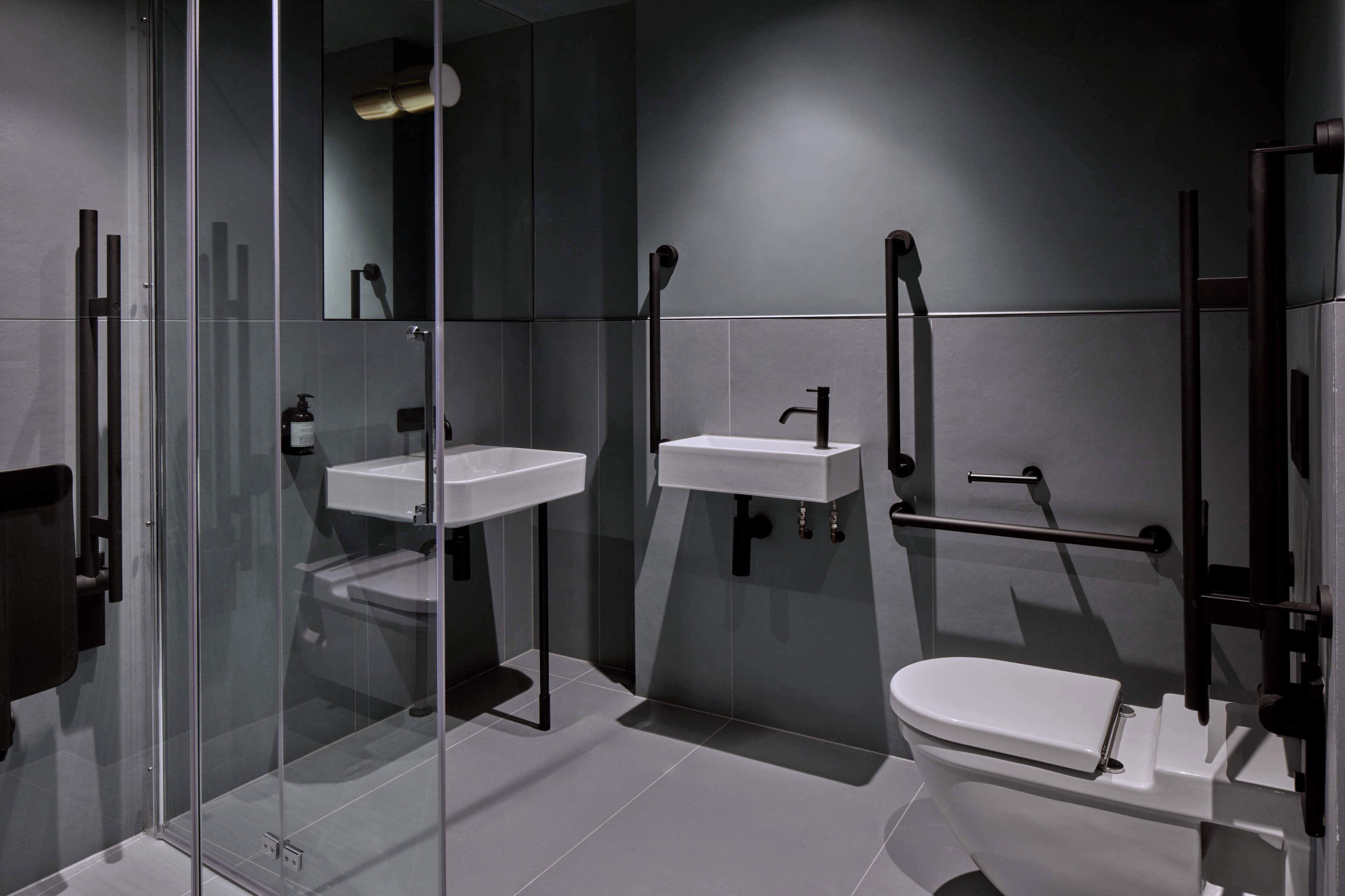 A modern bathroom with a glass shower enclosure, a white sink, and a toilet.