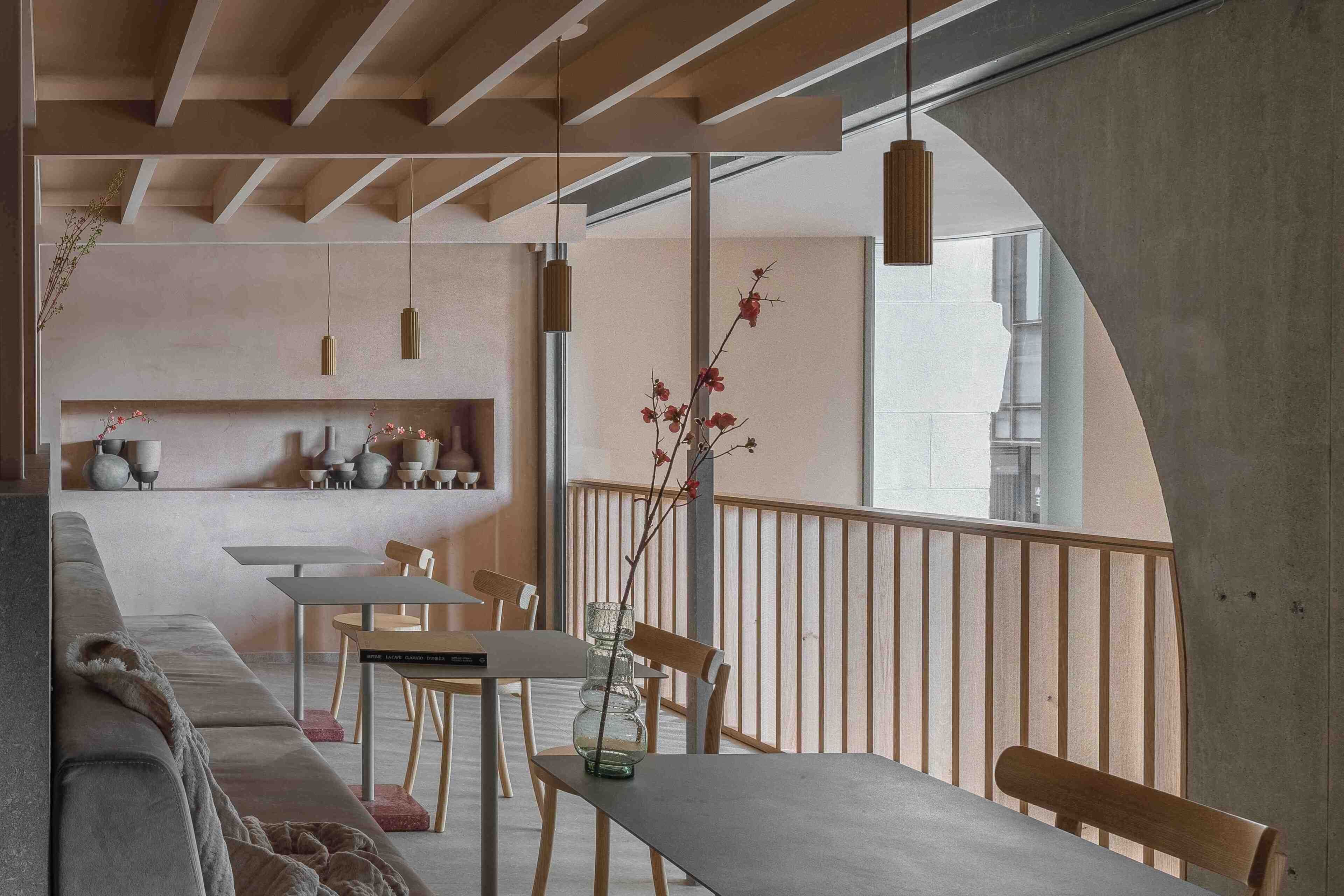 Un interior moderno con un sofá, una mesa de comedor, sillas y un florero con flores.