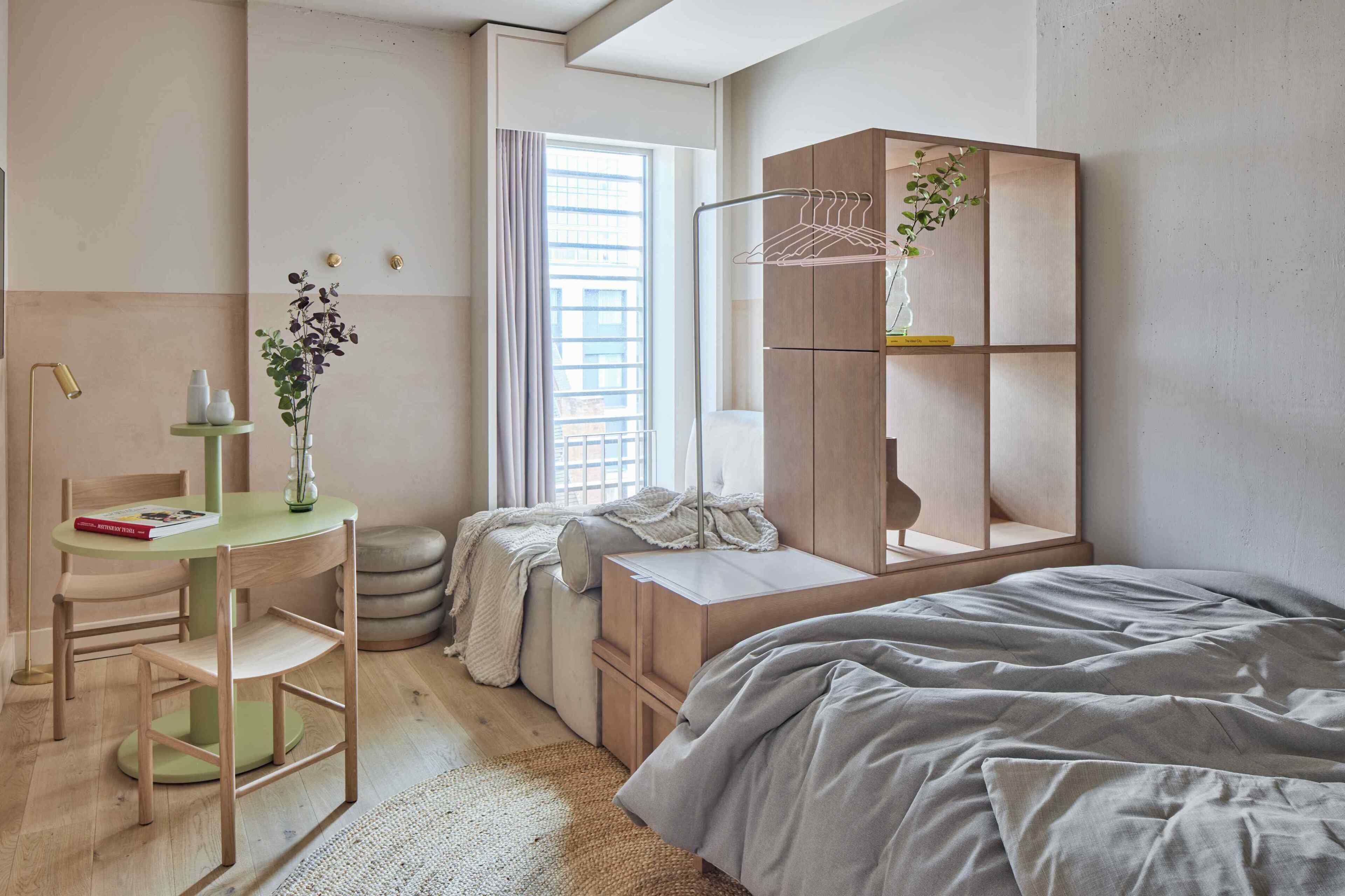 Un dormitorio con cama, escritorio con silla, armario y ventana con cortinas.