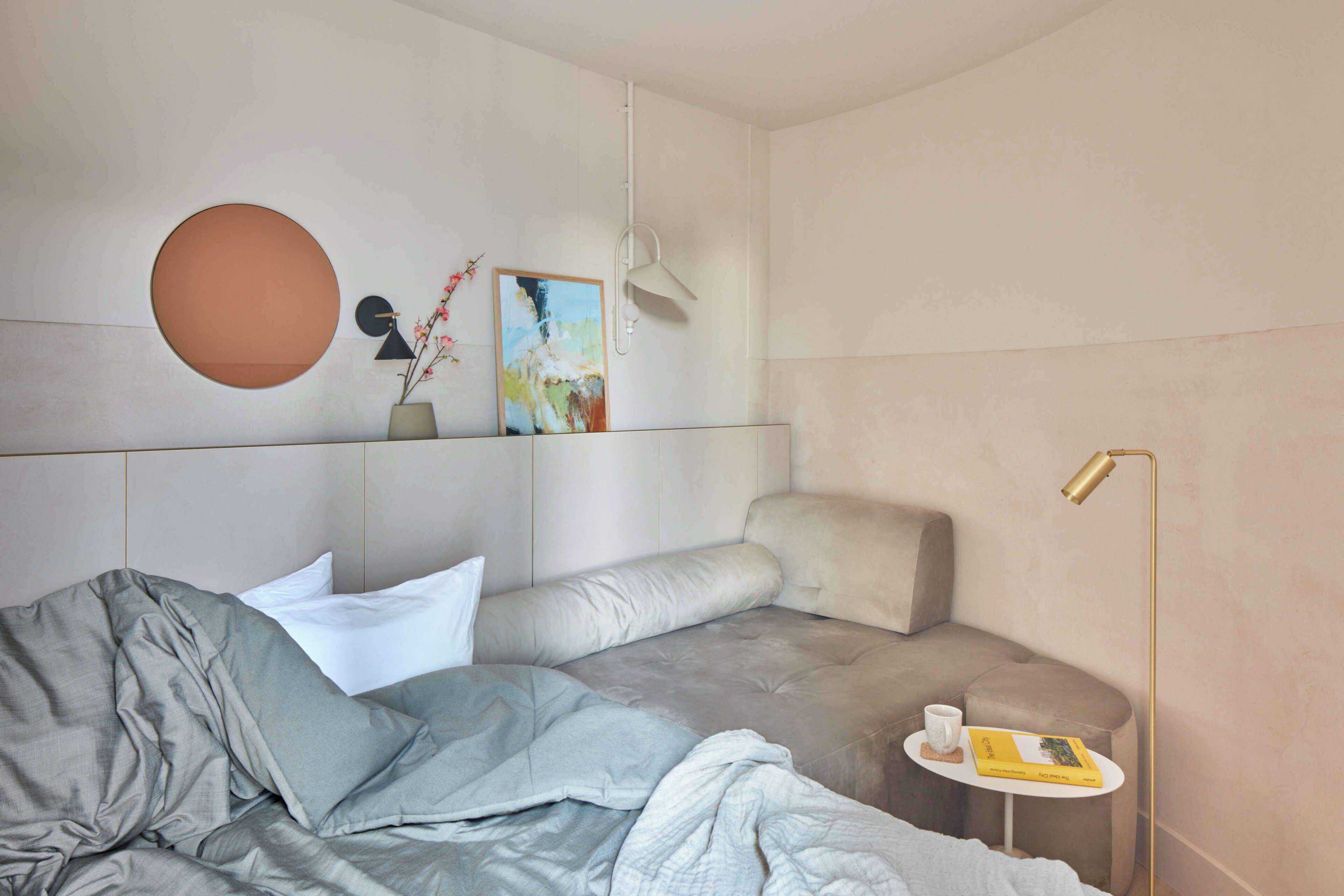 Et moderne soveværelse med seng, natbord, lampe og kunstværk.