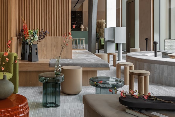 Um lobby moderno com balcão de recepção, áreas de estar e uma grande janela.