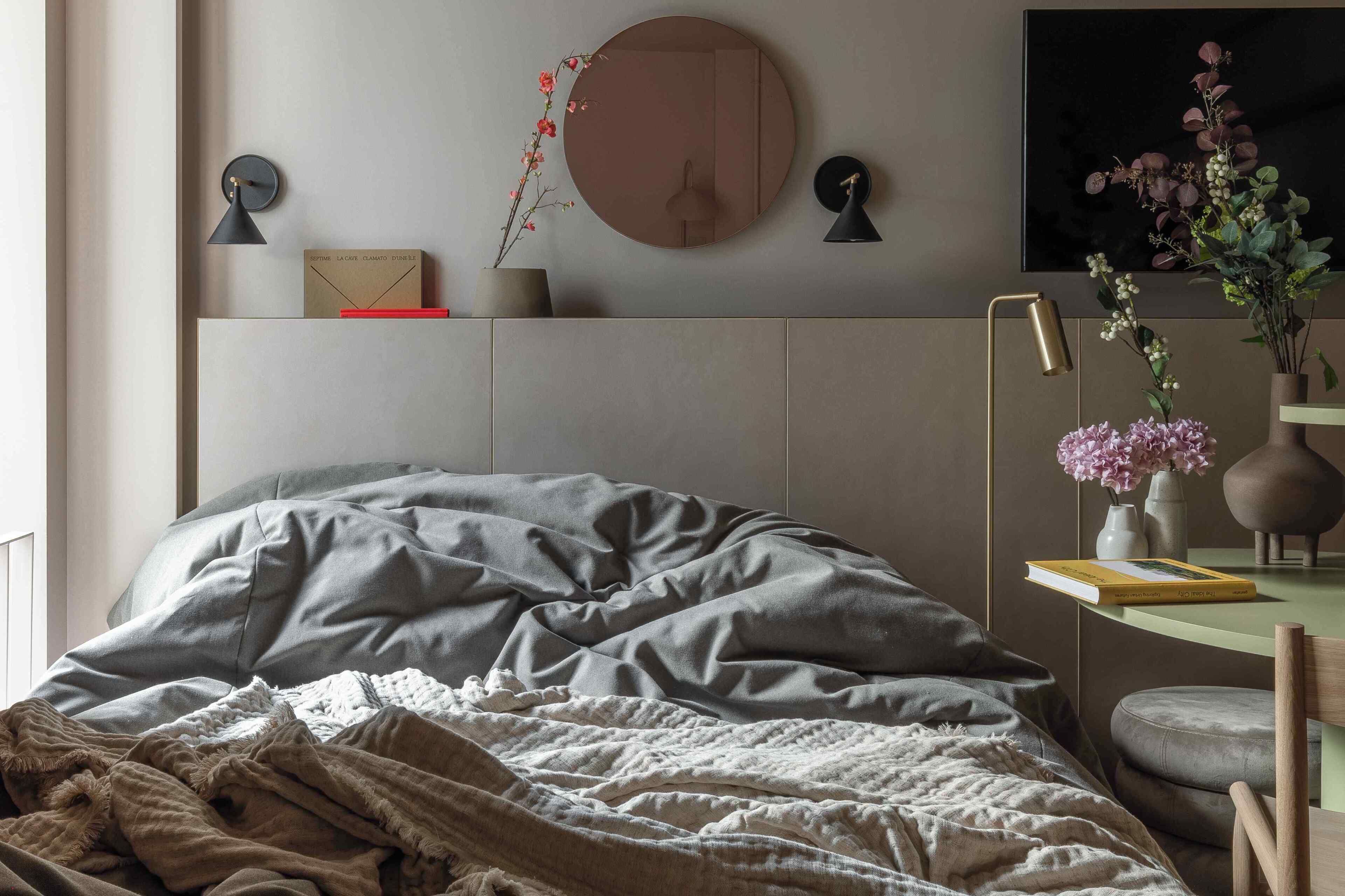A bedroom with a bed, bedside table, lamp, and wall-mounted decor.
