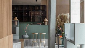 A modern interior with a bar area, stools, a vase with flowers, and a large window. - Buckle Street Studios by Locke, Aldgate (London)