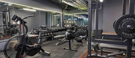 A gym with exercise equipment, weight racks, and a fan.