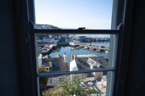 A view through a window of a coastal town with a harbor, buildings, and a bridge.