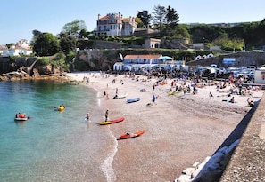 A crowded beach with kayaks and people.