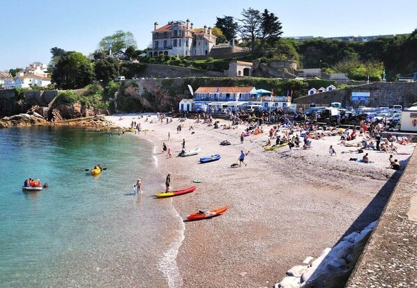 A crowded beach with kayaks and people.