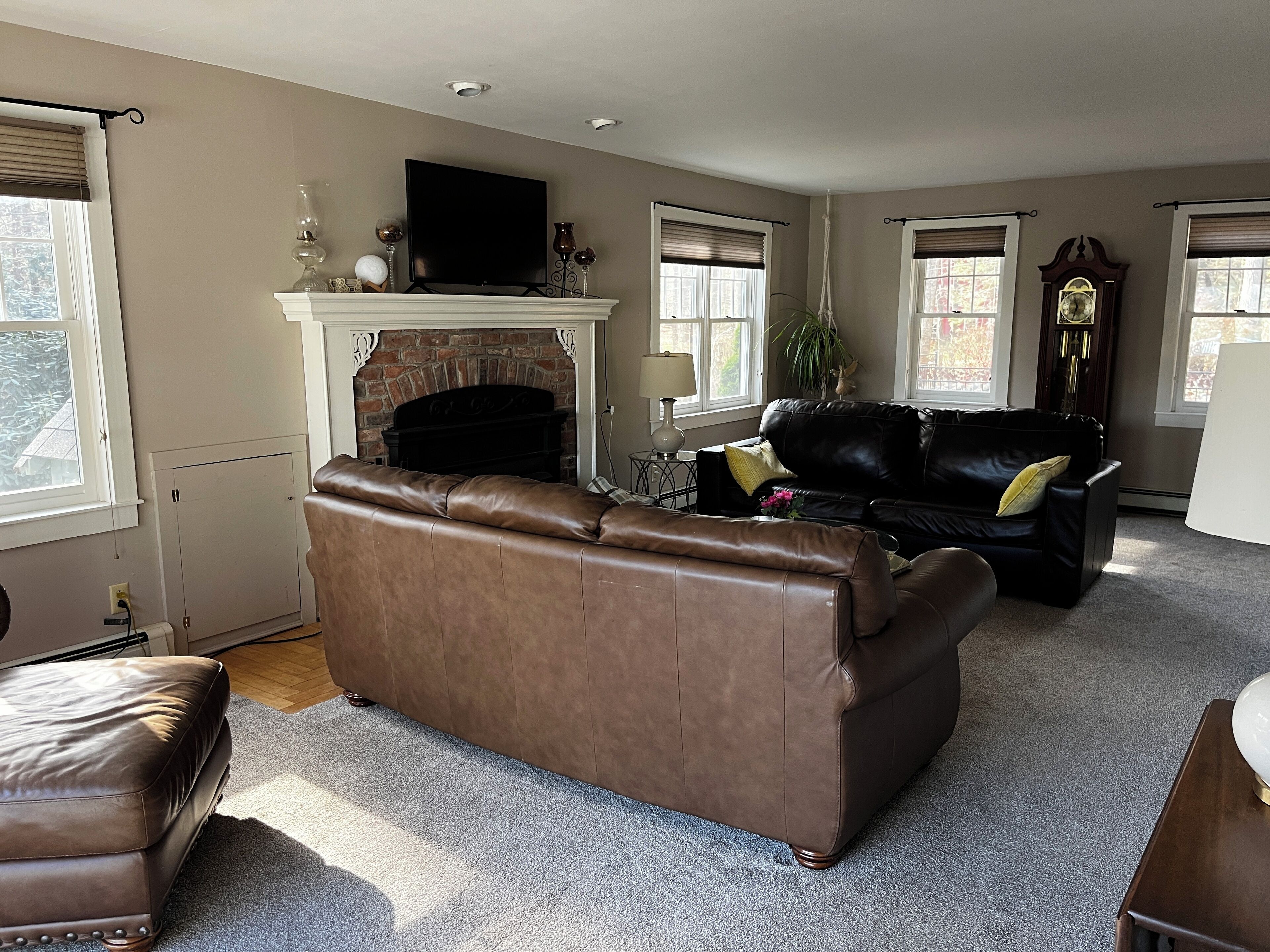 A living room with a fireplace, leather sofas, a television, and a clock on the wall.
