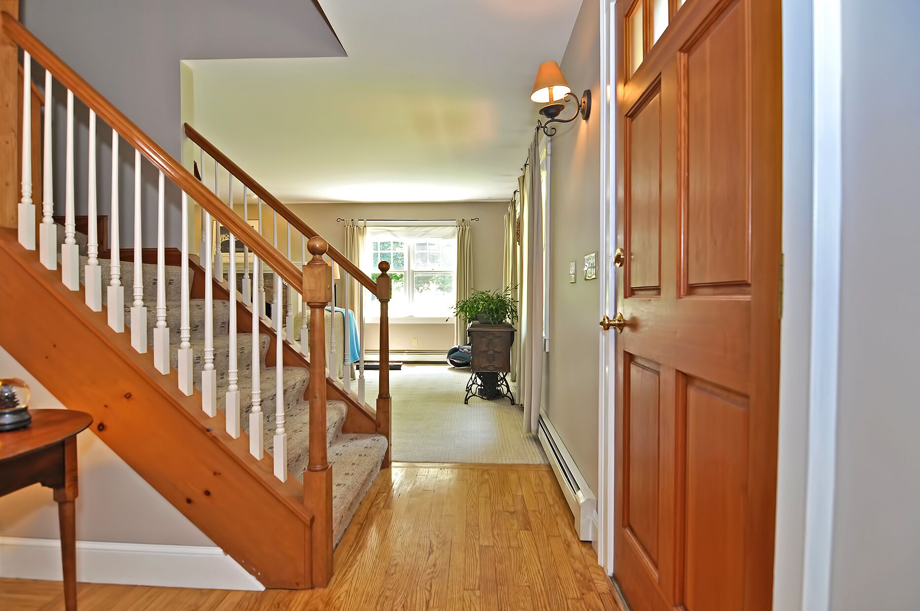 A wooden staircase leading to a room with a radiator and a potted plant.