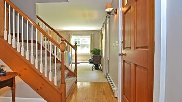 A wooden staircase leading to a room with a radiator and a potted plant.