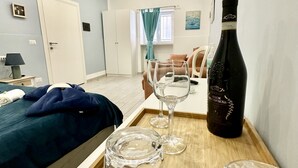 A hotel room with a bed, a wooden table with a bottle of wine, two wine glasses, and a tray. - Beautiful Big Studio for 4 people in the Heart of Naples 1B (Napoli)