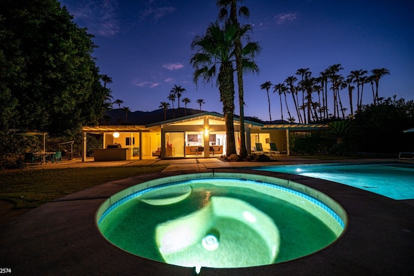 Une maison avec une piscine, au crépuscule.