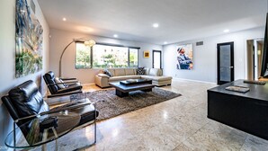 Ein geräumiges Wohnzimmer mit einer großen Couch, einem Couchtisch und einer TV-Konsole.