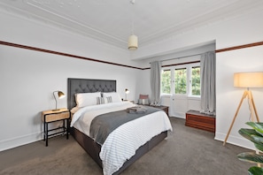 Cozy retreat with a large bed, bedside table, and potted plant.